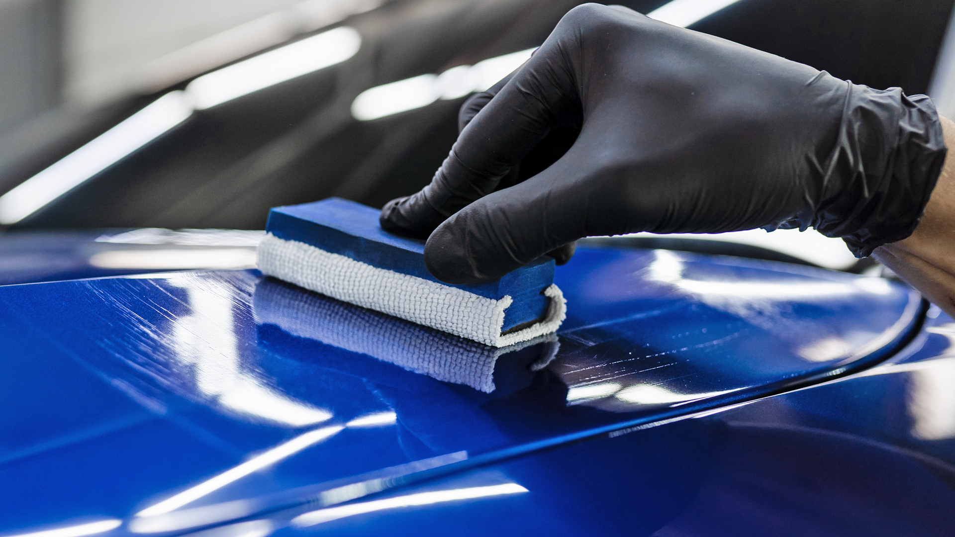 Ceramic coating being applied to car paint surface